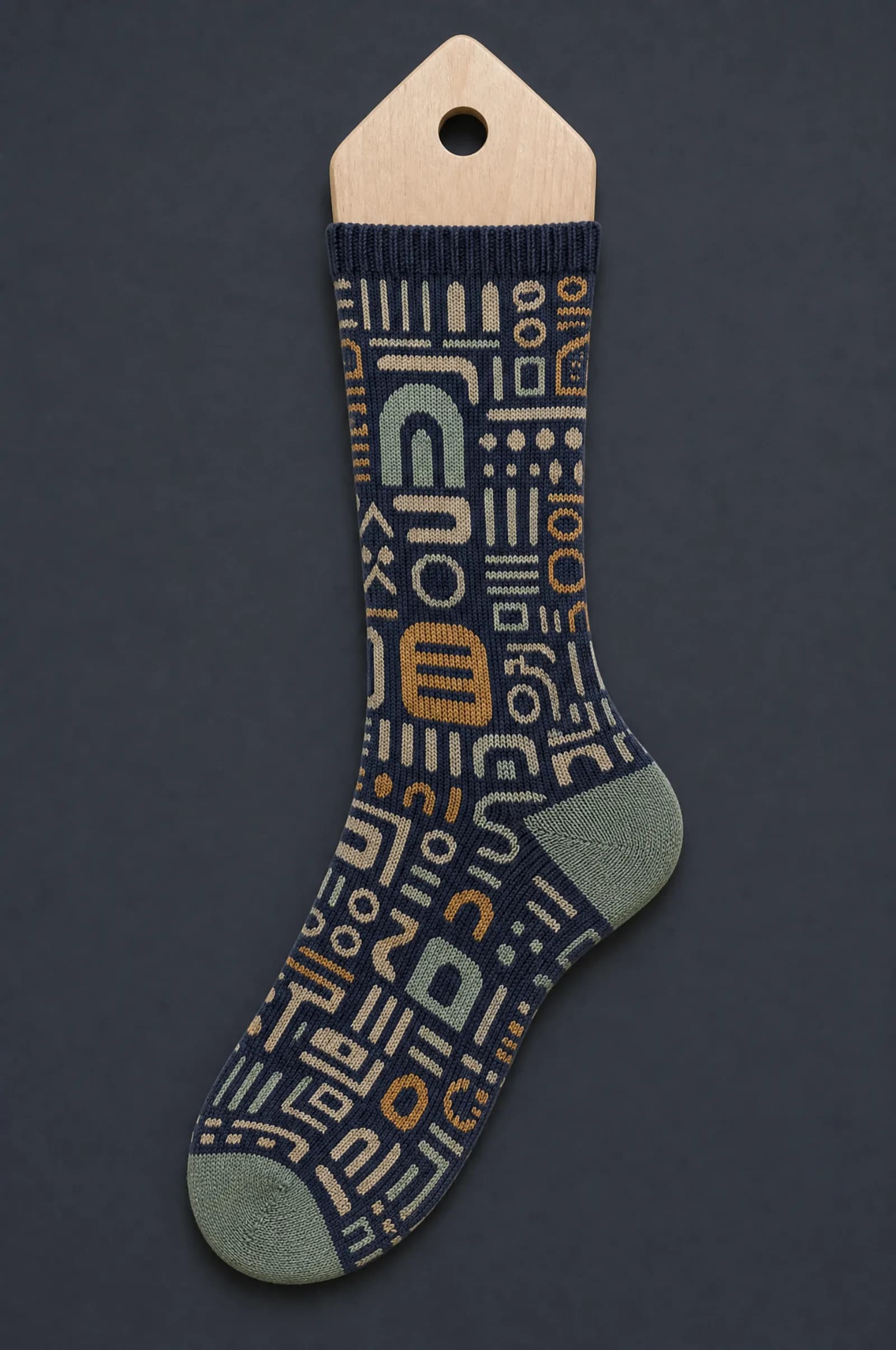 The Type Premium pattern on a sock stretched over a sock form, showing how the drawing curves and compresses