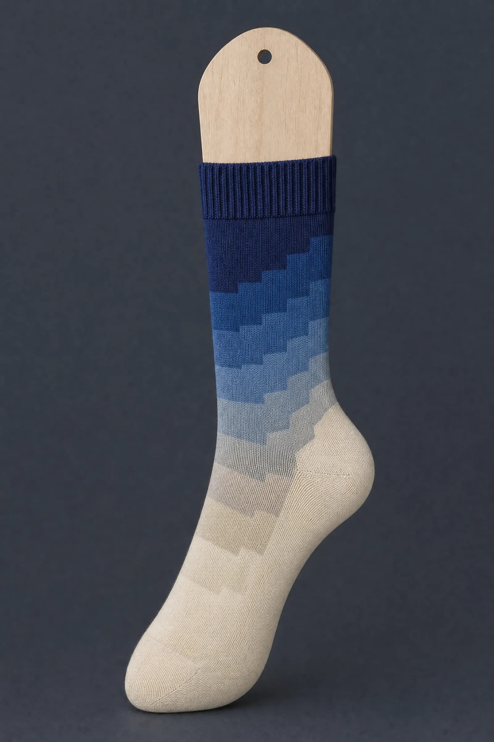 The Gradient Two pattern on a sock stretched over a sock form, showing how the drawing curves and compresses