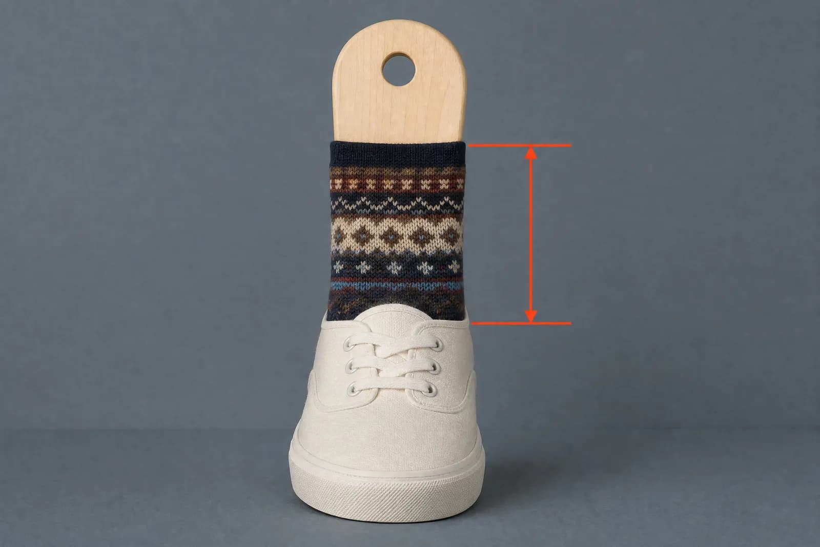 A patterned sock in a plain low-cut shoe with a vermilion bracket marking the shoe collar height