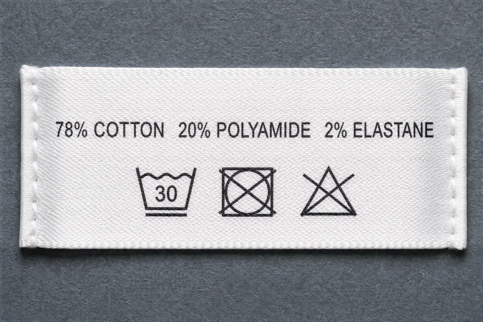 The sewn-in care label for Band Uneven, showing the fibre composition and wash symbols